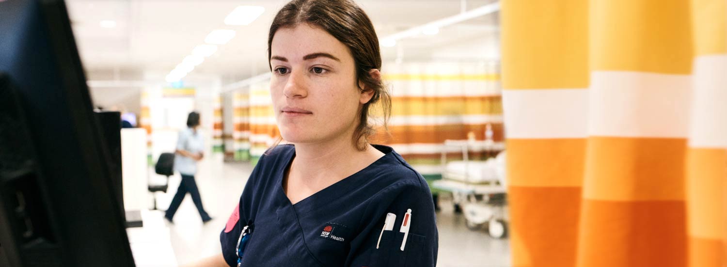 Female clinician in ward working at monitor