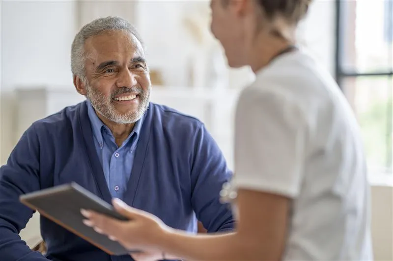 Ethnic man over 60 years speaking with health professional 